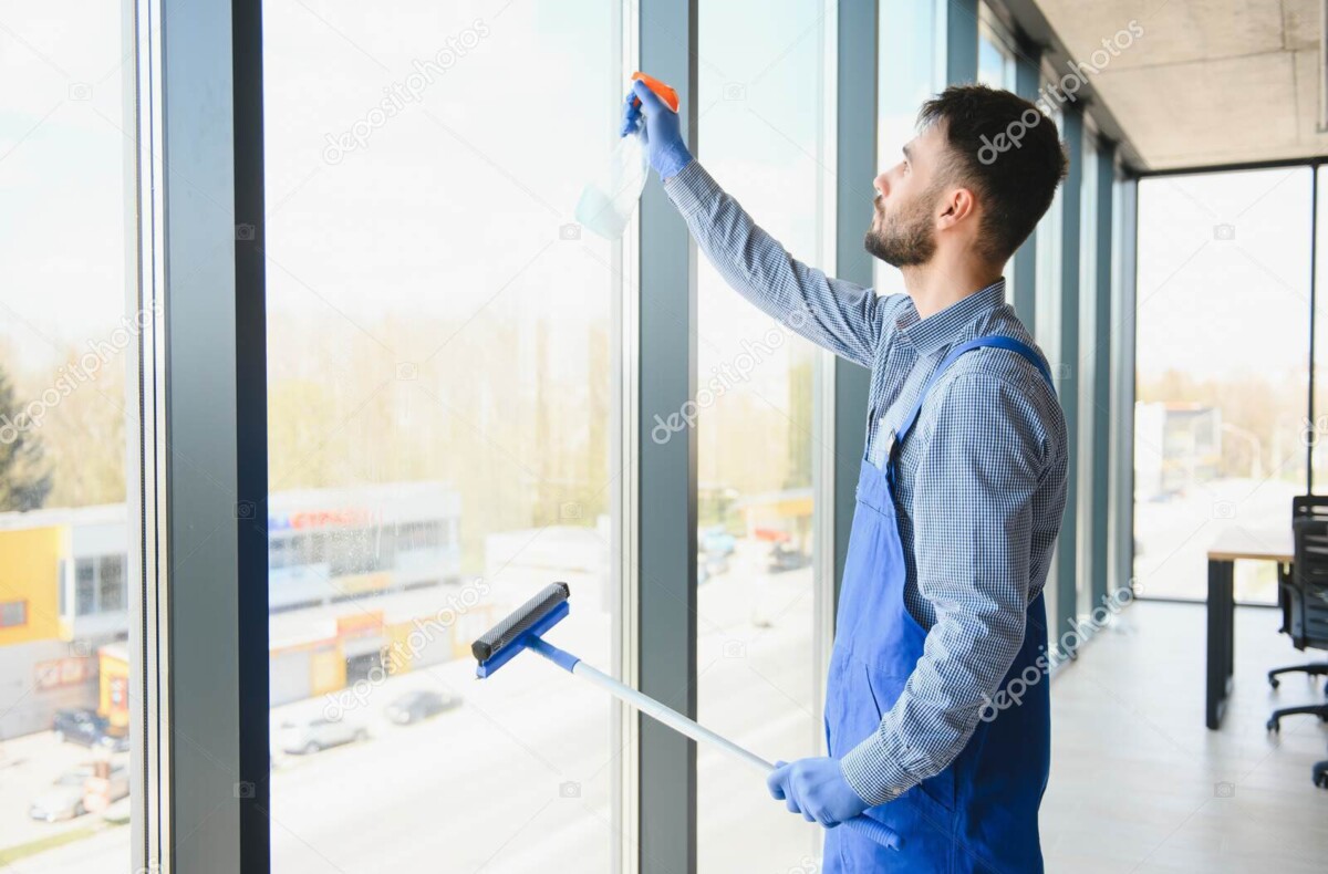 male janitor cleaning window in office
